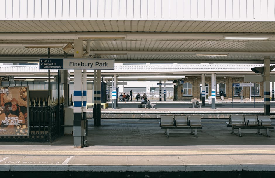 The image shows the platform at Finsbury Park train station during daytime, with several wooden benches arranged along the edge near the tracks. The station's canopy covers the platform, supported by 